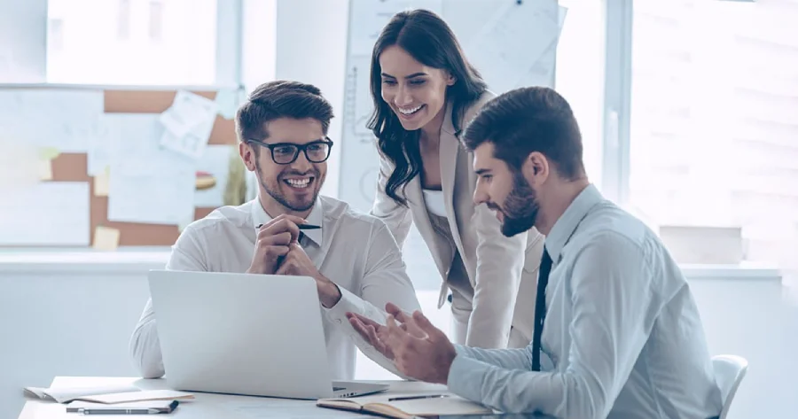 2 men and a woman are sitting in front of a laptop.