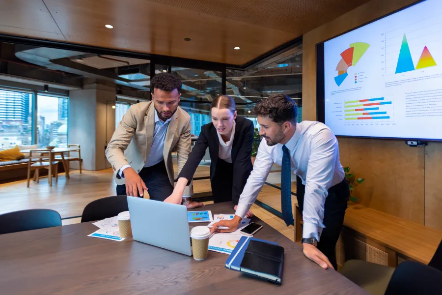 EdTech experts ( 2 men and 1 woman) are standing around a table looking at a laptop and discussing the EdTech 2.0: 7 Path-Breaking Technologies for Future EdTech Products