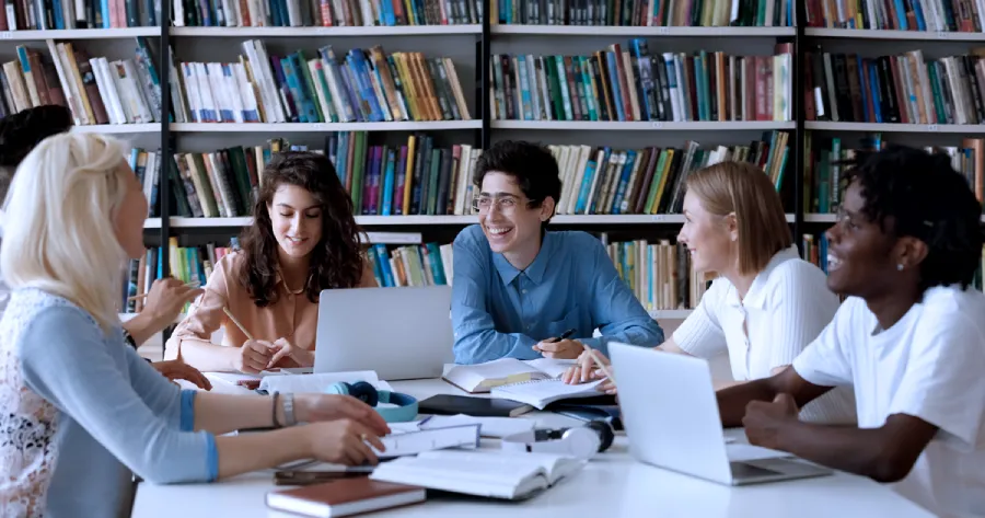 A group of students ( 3 women and 3 men) are studying together around a table.