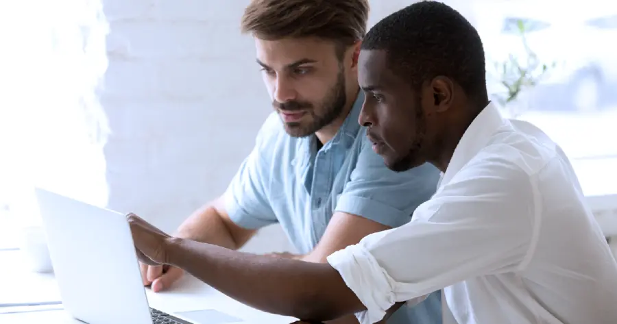  Two men working together on a laptop. 