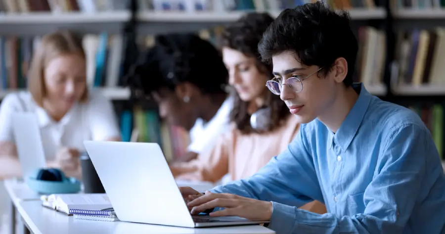  A student studying on a laptop in a library. 