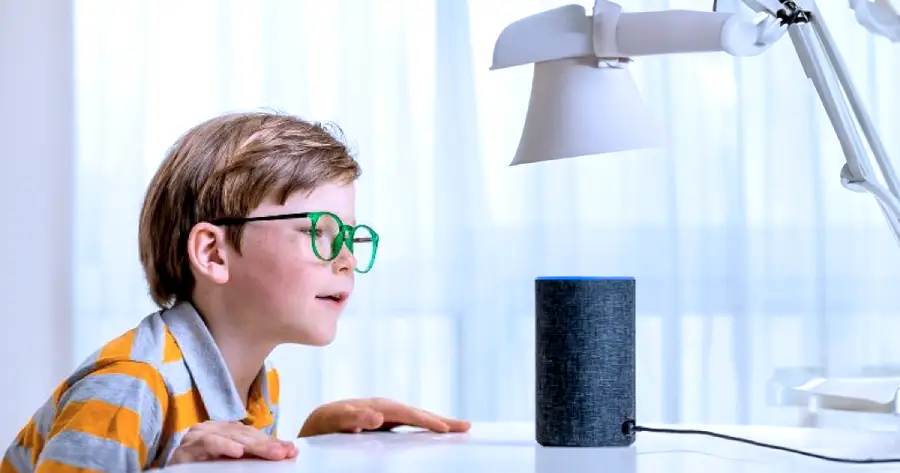 A boy speaking to a voice assistant device.