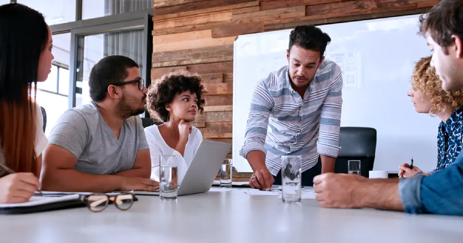 A team of men and women sitting around a table in a team meeting. 