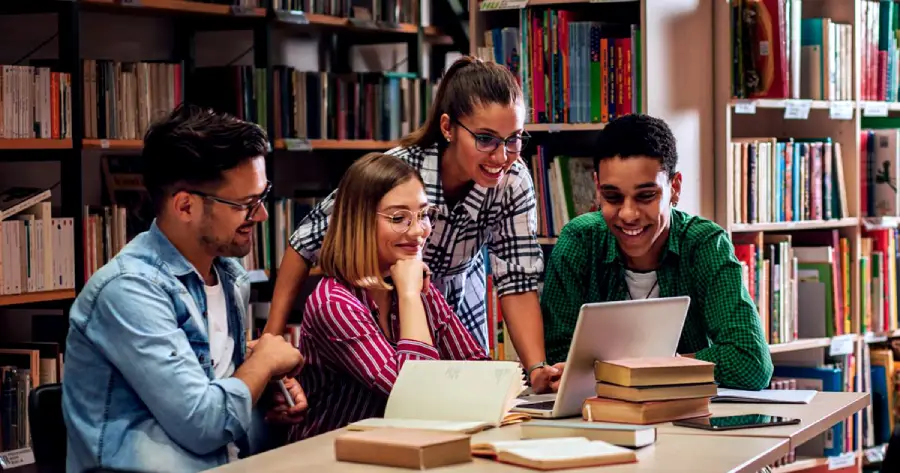 A group of students looking at a laptop together.