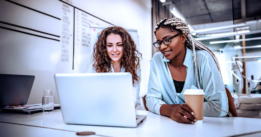  Two women looking at a laptop screen. 