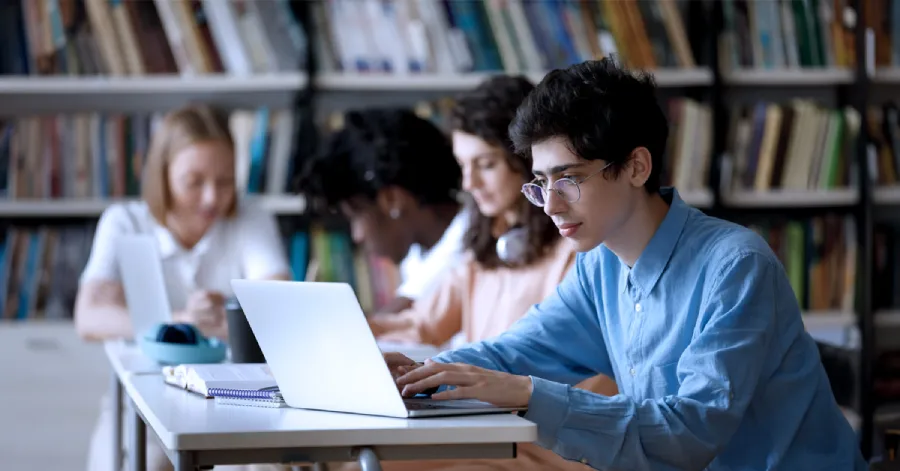 A male student wearing glasses studying an e-learning module.