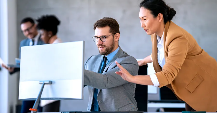 A man is interacting with AI on the desktop, and a woman is looking at it. 