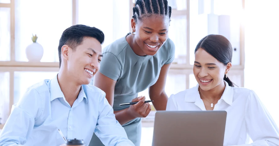 Three co-workers working on an immersive learning platform on a laptop. 