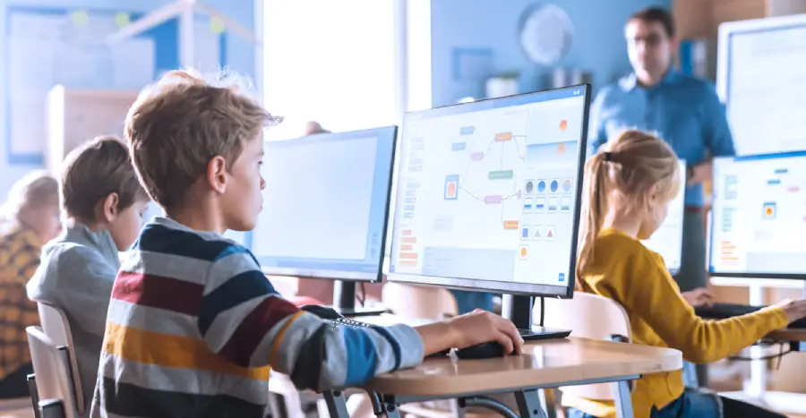 A boy student using an adaptive learning platform on a personal computer in a classroom.