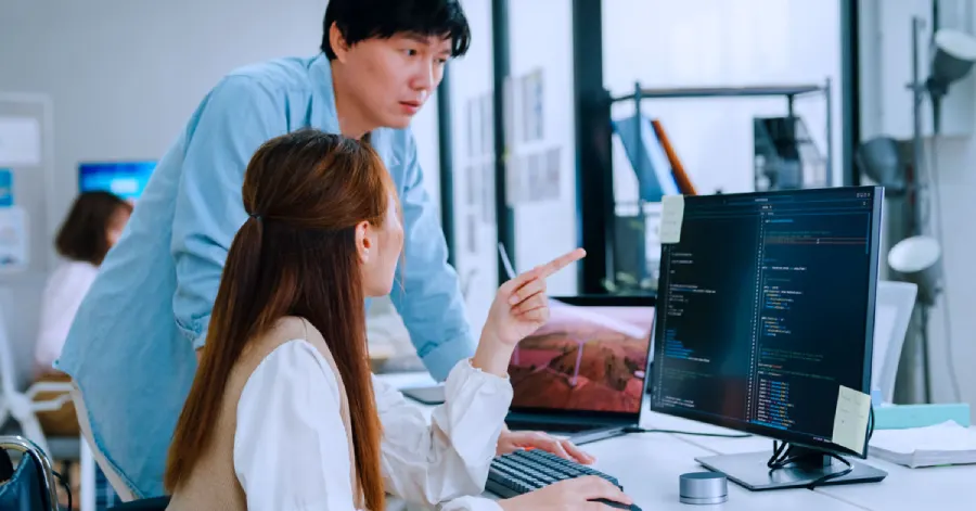 Two office workers, a man and a woman, are discussing whether their products adhere to voluntary product accessibility guidelines. 