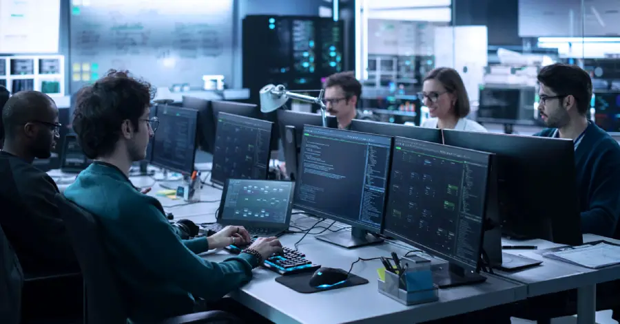 A group of men and women working in a research center using computers to do accessibility testing.
