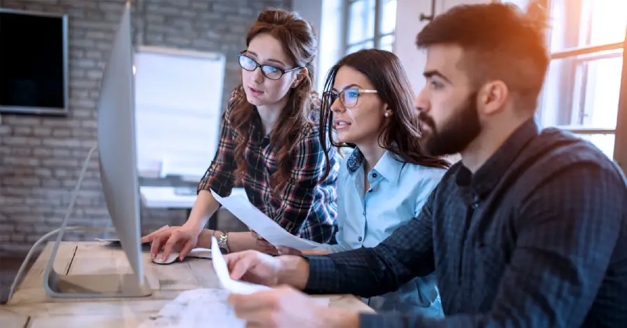 A team of three young cloud migration consulting services specialists working together in the office.
