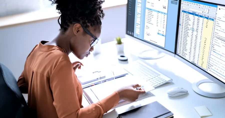 A professional African American woman conducting a Web Accessibility Audit sits at her desktop computer.