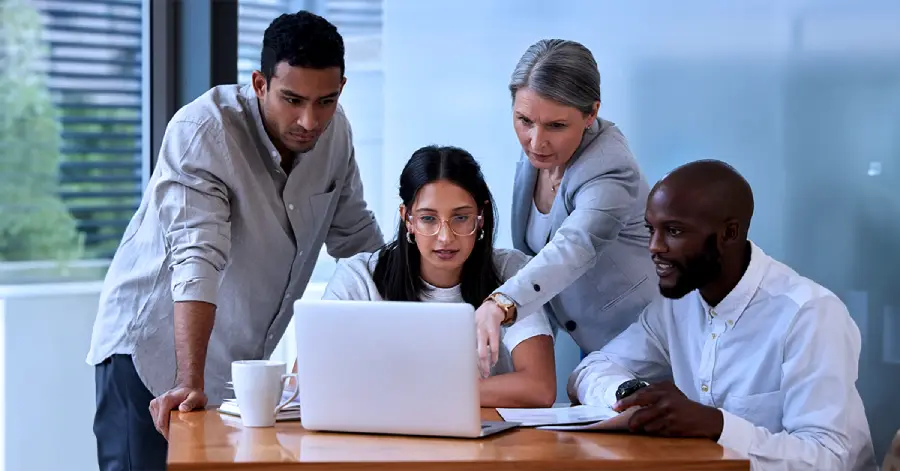 A group of multi-racial people in a CTE company working together on improving student engagement.